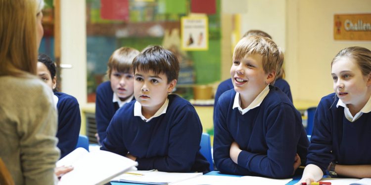 Nauczycielka mówi do uśmiechniętych uczniów, sala lekcyjna, klasa